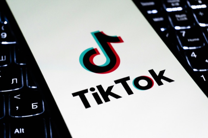 The TikTok logo on a phone screen resting on a laptop keyboard